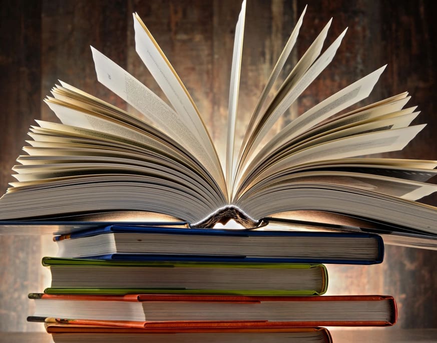 An open book with its pages fanned out is placed on top of a stack of closed books, each representing the principles of sustainable product design.